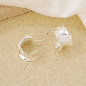 Macro shot of stylish silver chunky hoop earrings with an irregular wavy ripple texture