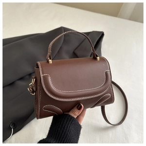 Close-up of a brown crossbody bag with contrast white stitching and top handle