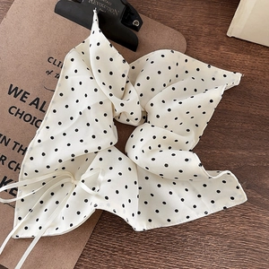 Cream polka dot scrunchie with large bow and white ribbons on a wooden surface
