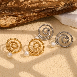 Detail of twisted gold and silver hoop earrings with white pearls on natural stones