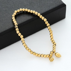 Detailaufnahme des goldenen Perlenarmbands mit Herz- und Blumenanhänger auf Schmuckschatulle