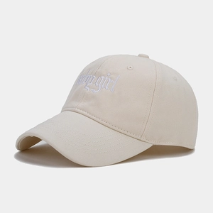 Close-up of white babygirl embroidery and stitched brim on a beige cotton baseball cap