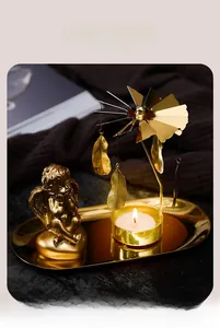 Detail of golden spinning candle holder with feather pendants and angel statue on a tray