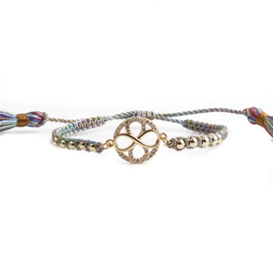 Detail of infinity charm with white zircons and colorful braided cord on gold bracelet