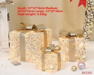 Close-up of LED Christmas gift boxes with gold bows and warm glowing weave texture
