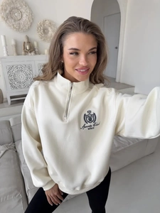 Detail of half-zip sweatshirt featuring embroidered sports club crest on premium fabric