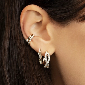Close-up of pavé zircon gold hoop earrings and ear cuffs styled with a layered look