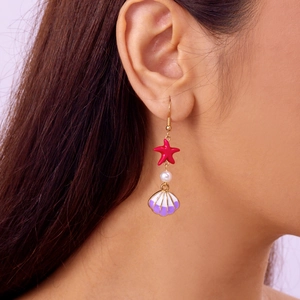 Detail of a sea-themed earring with a red starfish, pearl bead, and shell pendant