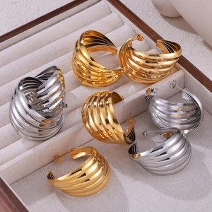 Modern twisted C-shape hoop earrings in gold and silver finish on display tray