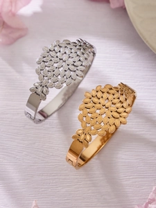Detailed close-up of hollow leaf pattern on 18k gold and silver stainless steel bangles