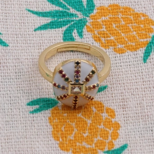 Detail of copper ring featuring square zircon stone and colorful pavé stones in gold finish
