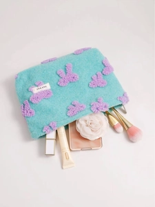Blue plush cosmetic bag with purple bear embroidery and makeup accessories inside