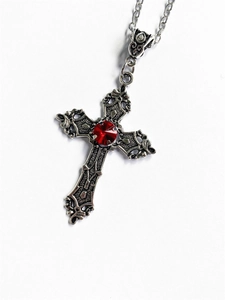 Close-up of vintage silver cross necklace with a faceted red gemstone on white background