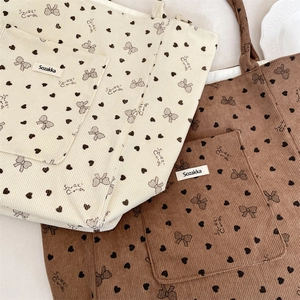 Detail view of corduroy tote bags in cream and brown with sweet candy heart patterns