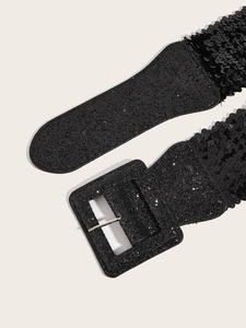 Détail d'une ceinture élastique à paillettes noires avec boucle carrée scintillante sur blanc