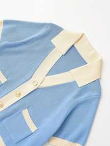 Detail of light blue and beige knit cardigan with textured gold buttons and pockets