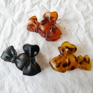 Three bow-shaped hair claws in matte black and amber tortoise shell resin patterns