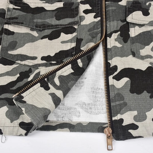Macro view of ripstop camouflage fabric with metal zipper and tactical pocket detail