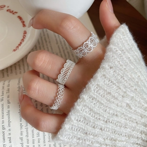Detailed view of silver lace-textured cubic zirconia rings worn as a layered stack