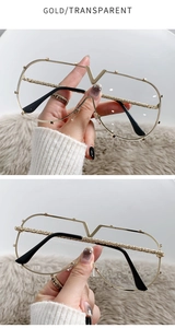 Detailed close-up of gold V-shaped metal bridge and transparent lenses on oversized glasses