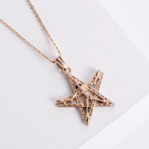 Punk style rose gold pentagram necklace with central skull pendant on white background