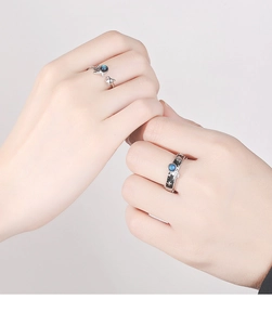 Close-up of astronaut couple rings featuring blue glazed stones and silver finish
