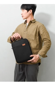 Vertical detail of black Oxford laptop bag with top handle and brown leather patch