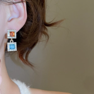 Gros plan de boucles d'oreilles carrées avec cristaux ambrés et bleus sur un mannequin