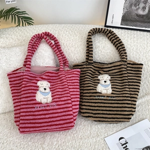 Detail of striped fleece tote bags with happy dog embroidery and plush texture