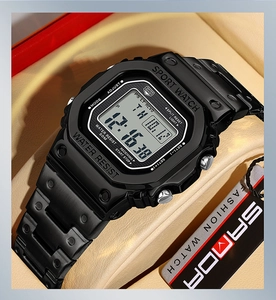 Detail view of the black SANDA sport watch on a beige display cushion with clear LED display