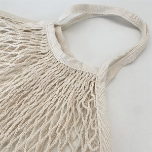 Détail du sac en maille beige avec poignées renforcées en tissage à chevrons pour durabilité