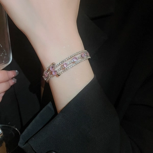 Close-up of a silver multi-layer cuff bracelet with pink zircon stones on a female wrist