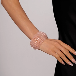 Gros plan d'un large bracelet en acrylique rose poudré au design géométrique modulaire