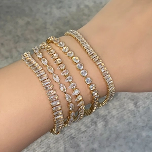 Detailed close-up of five layered gold bracelets featuring various cubic zirconia cuts