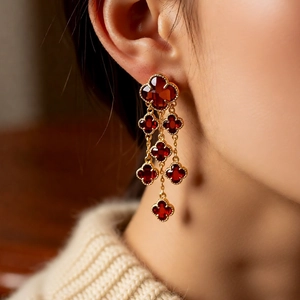 Detail of vintage 18k gold plated long tassel earrings with red floral glass drops on a model