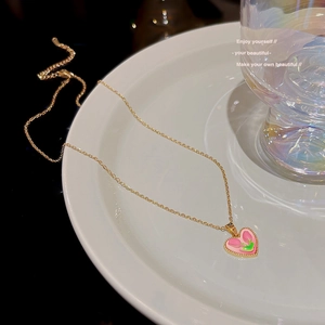 Detail of 18K gold tulip heart pendant on a pearl necklace shown in creative flat lay