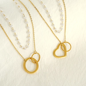 Gros plan d'un collier à double chaîne dorée élégant avec perles et pendentifs cœur