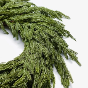 Detailed close-up of premium PE cedar wreath needles on a natural rattan base for Christmas