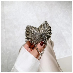 Detail of silver heart-shaped mini bag with radial pleated metal texture and chain strap