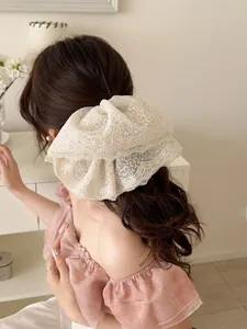Detailed view of an elegant white embroidered lace scrunchie styled on a bun hairstyle