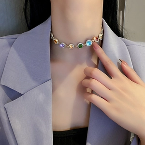 Close-up of a colorful gemstone choker necklace with gold plating worn by a model