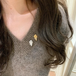 Elegant gold and silver feather brooches with zircon on a grey knitted sweater