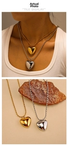 Macro detail of puffy heart pendant necklaces in gold and silver finishes on stone