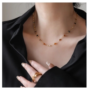 Close-up of a gold necklace with multi-colored natural stones on a model in a black shirt