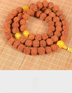 Macro shot of natural 5-mukhi rudraksha beads with amber resin spacers on bamboo mat