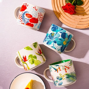 Nordic ceramic mugs with colorful tropical floral patterns on a textured surface