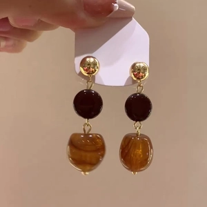 Close-up of vintage drop earrings with red and amber textured beads on white card