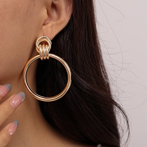 Close-up of elegant gold circular earrings featuring a triple-loop accent on model
