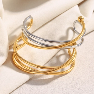 Bracelets croisés en acier plaqué or 18 carats sur un fond en tissu texturé crème
