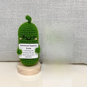 Close-up of handmade crochet emotional support pickle with positive message card